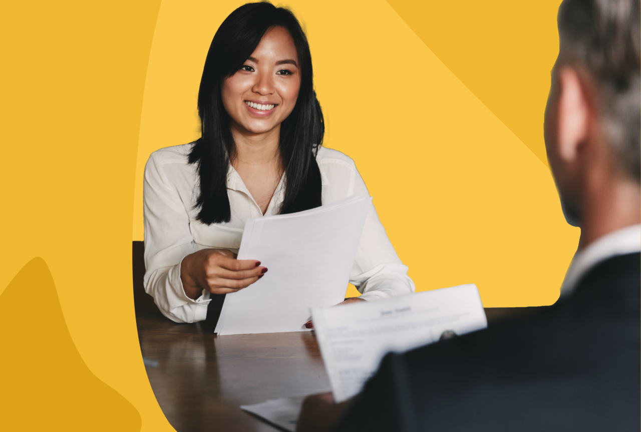 Woman holding paper, presumably an employment offer, and smiling.