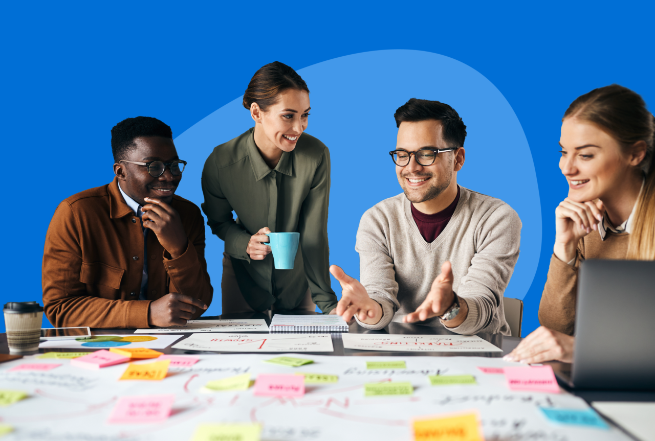 A cheerful team grouped around a whiteboard on a table with colorful sticky notes.