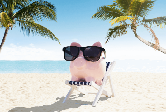 Piggy bank in a beach chair wearing sunglasses on a beach