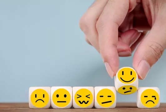 Dice lined up with all kinds of different happy faces on them with different expressions