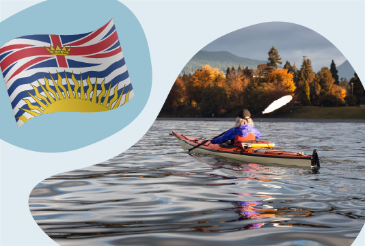 A flag of British Columbia next to a person kayaking on a lake.